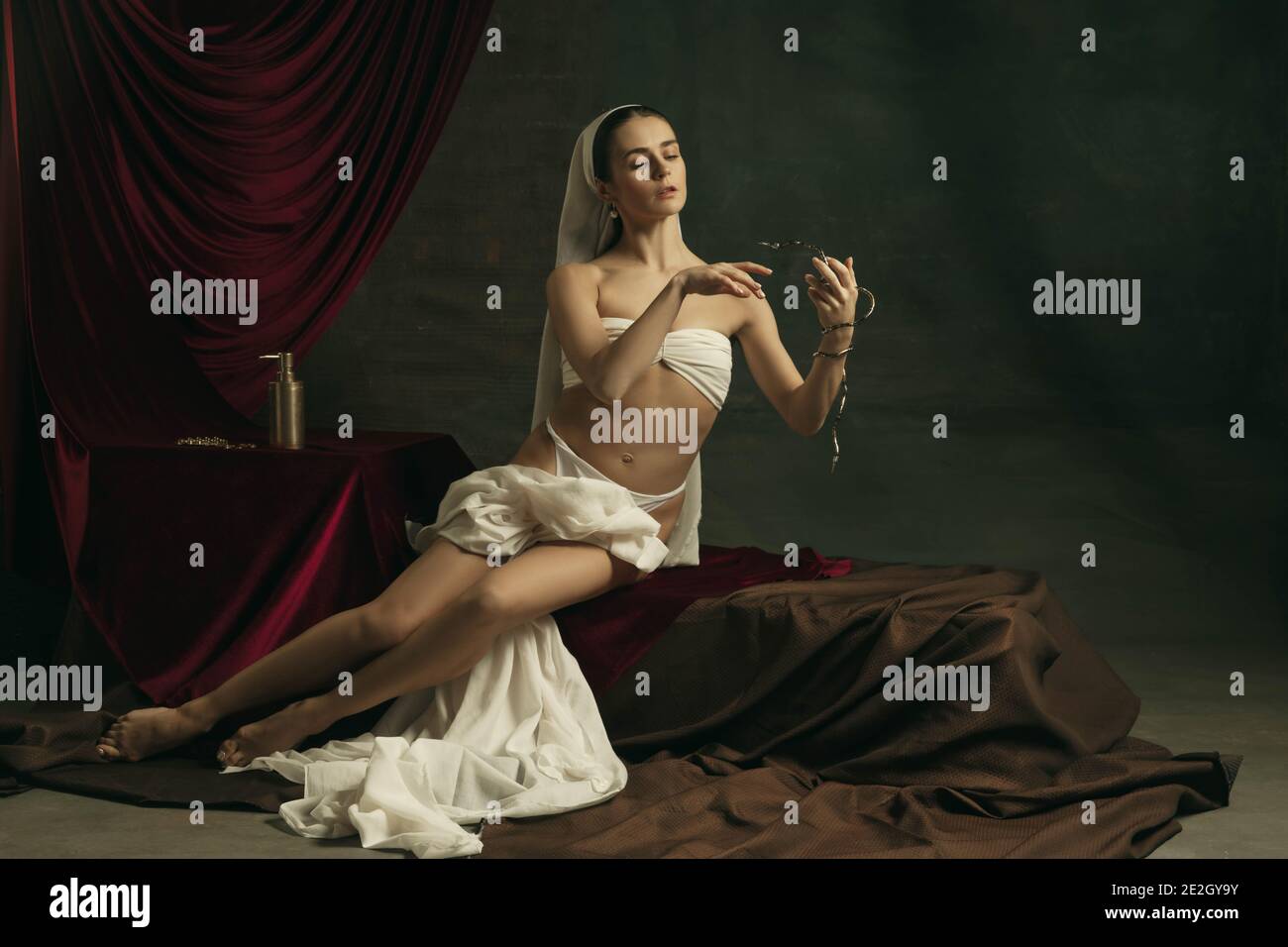 Sofferenza. Moderna remake di opere d'arte classica con tema coronavirus - giovane donna medievale su sfondo scuro in posa con medicina d'oro, pillole. Concetto di coronavirus, pandemia, creatività. Foto Stock