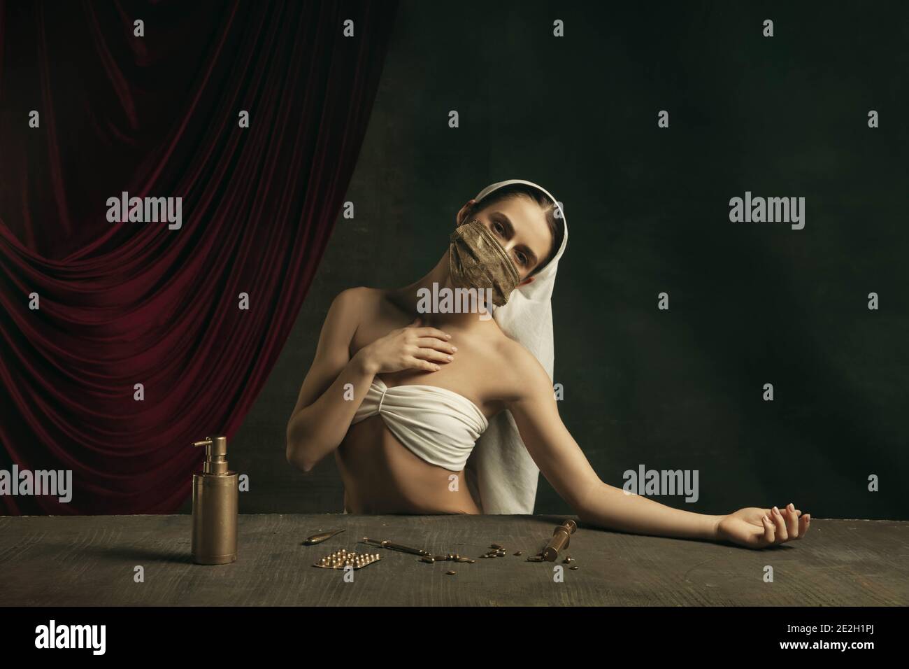 Medico. Moderna remake di opere d'arte classiche con tema coronavirus - giovane donna medievale su sfondo scuro in posa con maschera dorata e medicina. Concetto di coronavirus, pandemia, creatività. Foto Stock