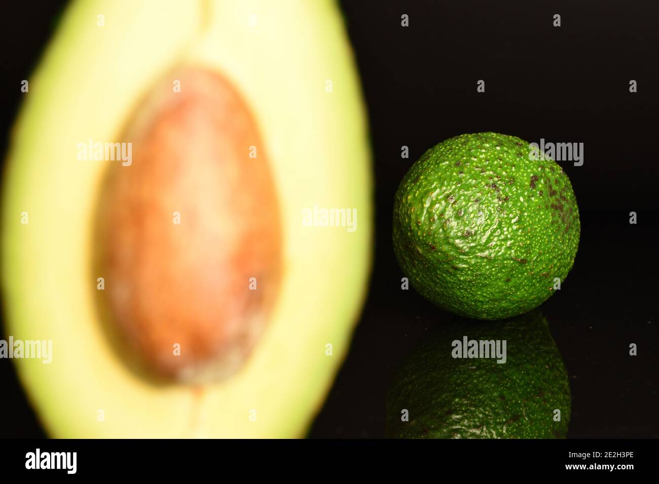 Parte di mezzo con osso, avocado fresco fresco naturale maturato - non a fuoco. Sullo sfondo, un intero avocado, in primo piano Foto Stock