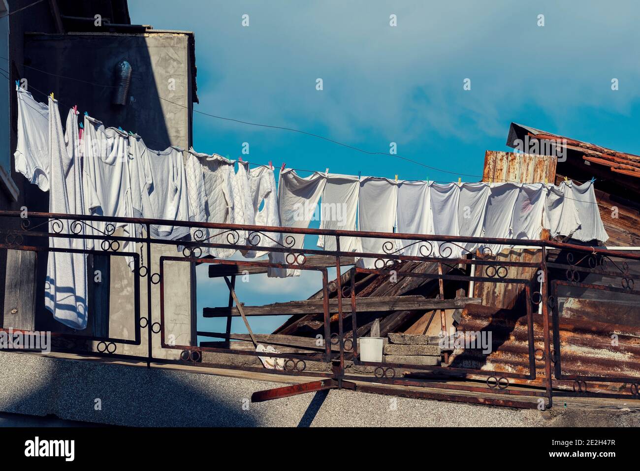 Bucato bianco appeso su un filo e asciugando sul sole sul tetto una vecchia casa in una piccola città Immagine orizzontale Foto Stock