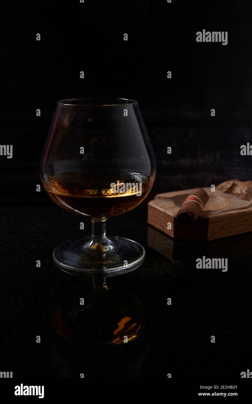 Brandy, Cognac, in Brandy Balloon, vetro di cristallo vintage con un sigaro Havan in un posacenere di legno fatto dal topo uomo. Foto Stock