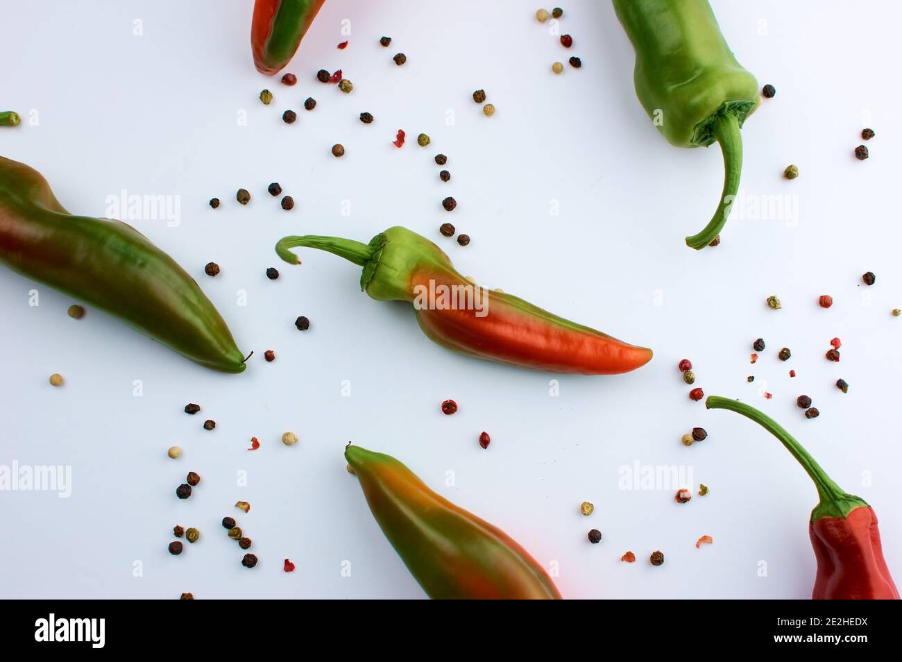 Fagioli di allspice. Grani colorati di pepe. Stagionatura. Una cialda di peperone rosso immacato. Su sfondo bianco. Foto Stock