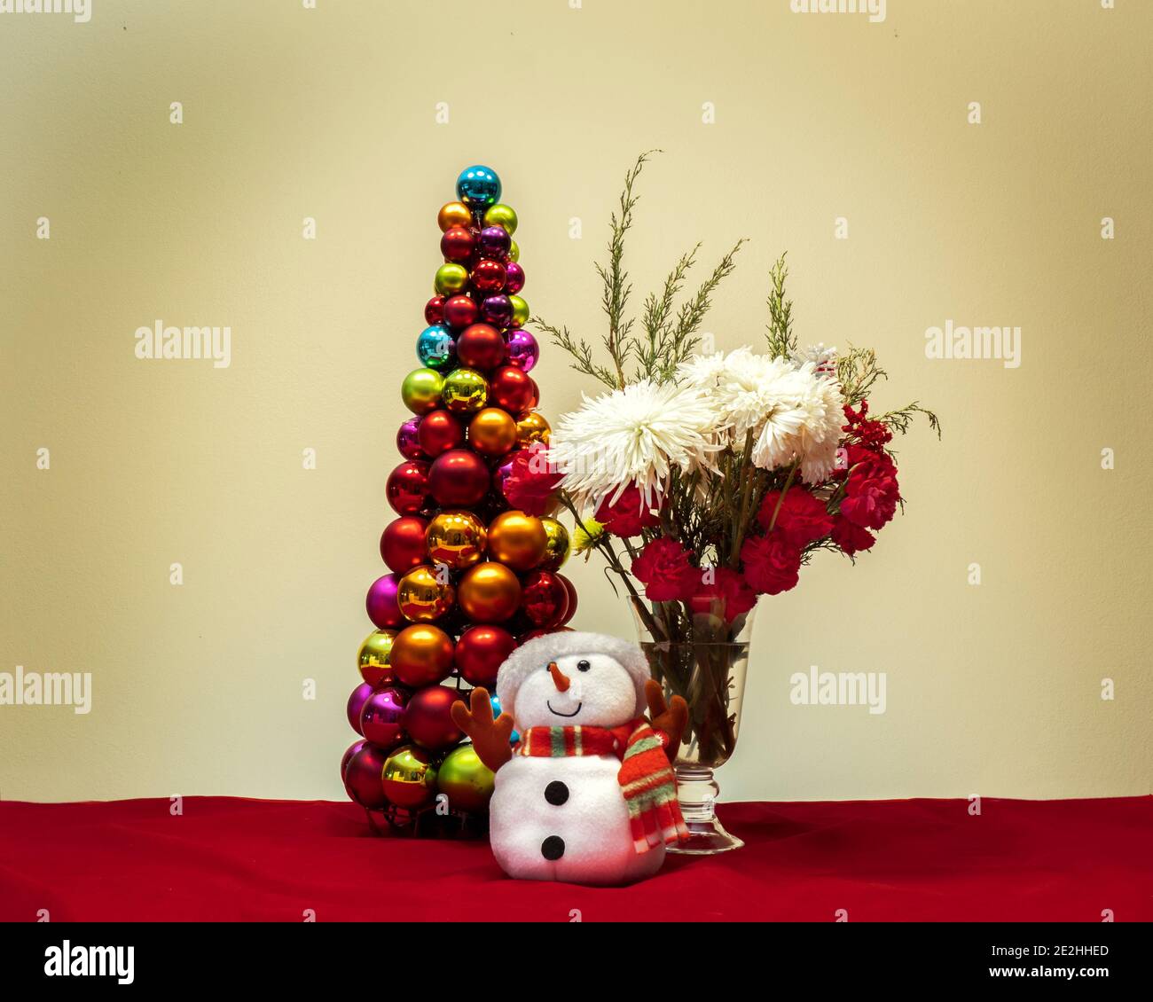 Scena di Natale con fiori pupazzo di neve e albero di natale fatto di decorazioni a sfere decorative lucide Foto Stock