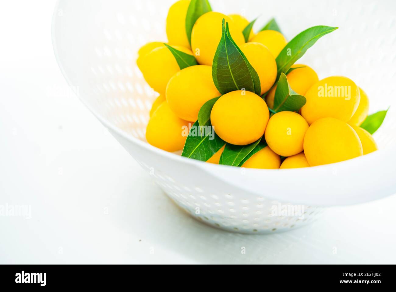 Primo piano frutta in cesto, bel mazzo di prugne mariane o mazzo di prugne mango in moderno cesto bianco di plastica, frutta tropicale della Thailandia, dolce e aside Asia Foto Stock