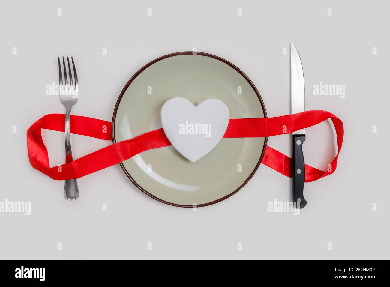 Concetto romantico di cena di giorno di valentines. Cuore su piatto e argento su sfondo bianco. Foto Stock