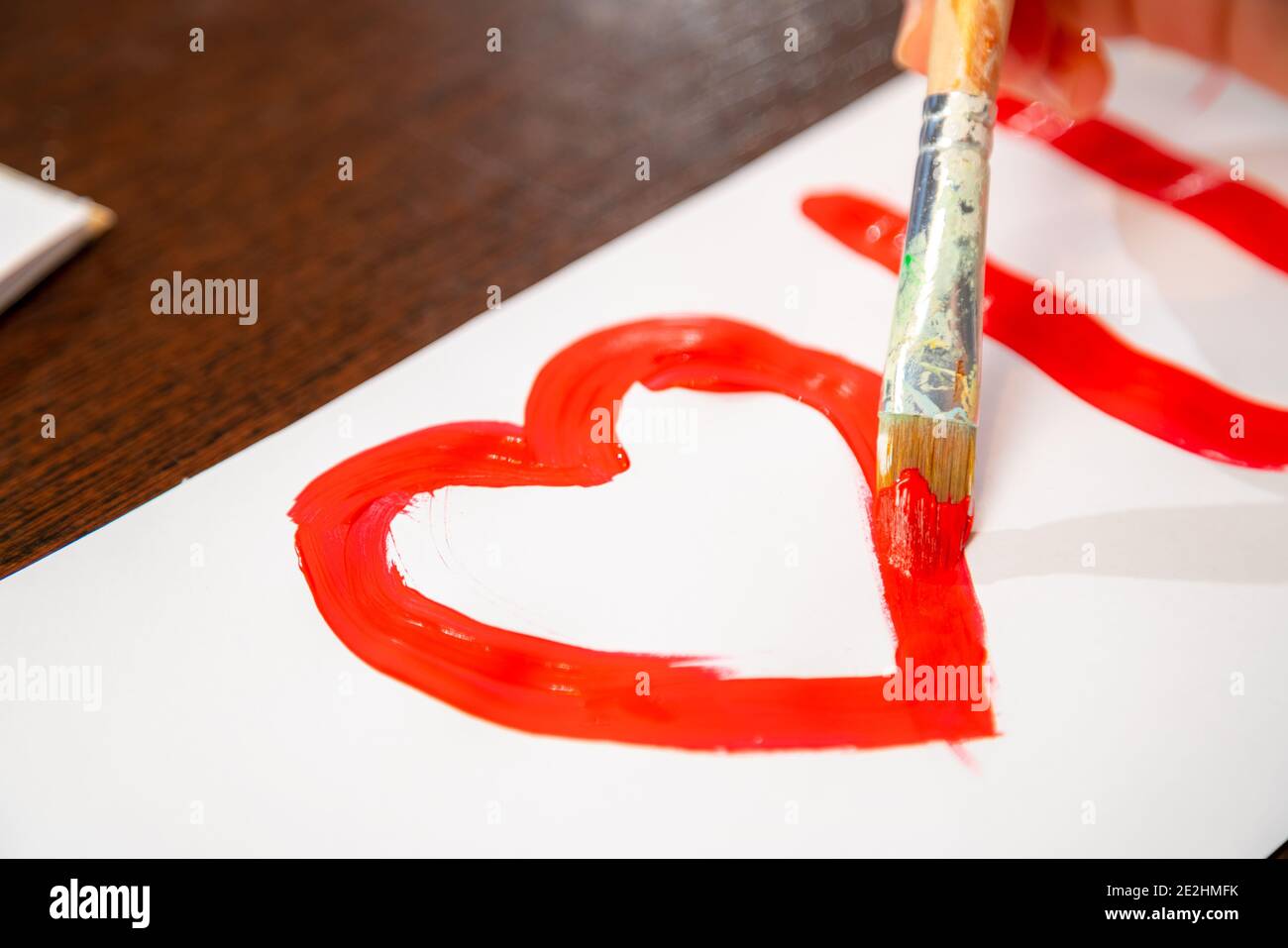 Pittura a mano vi amo con vernice rossa su carta bianca. Primo piano sulla creazione del biglietto di auguri di San Valentino. Foto Stock