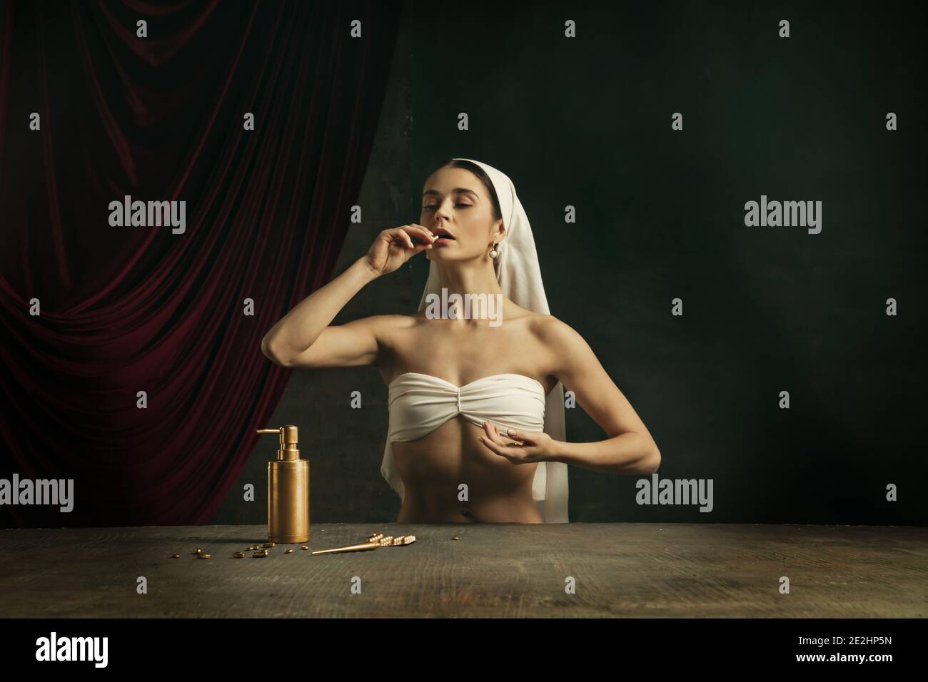 Trattamento. Moderna remake di opere d'arte classica con tema coronavirus - giovane donna medievale su sfondo scuro prendendo pillole di colore dorato. Concetto di coronavirus, pandemia, creatività, arte Foto Stock