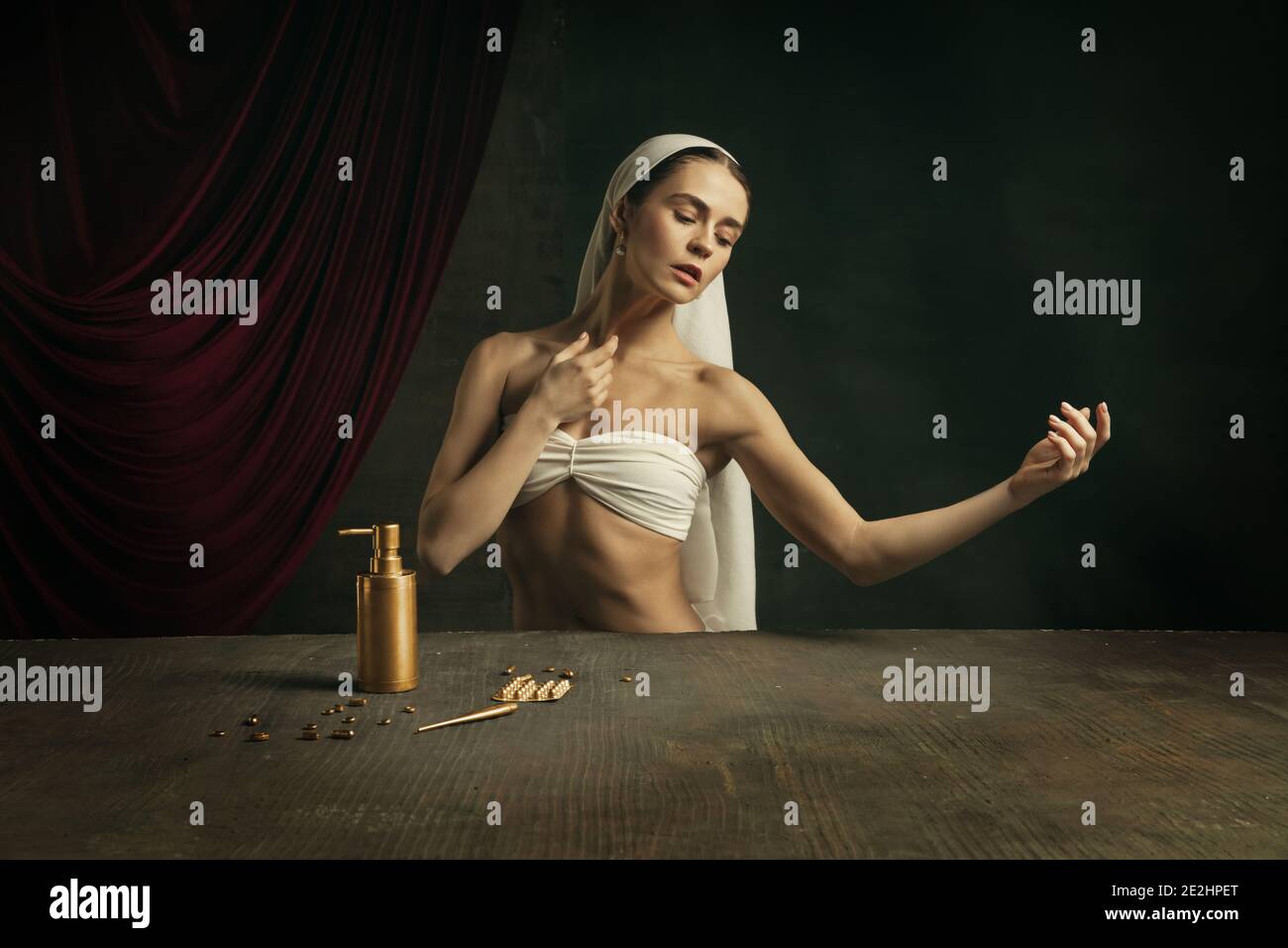 Trattamento. Moderna remake di opere d'arte classica con tema coronavirus - giovane donna medievale su sfondo scuro prendendo pillole di colore dorato. Concetto di coronavirus, pandemia, creatività, arte Foto Stock