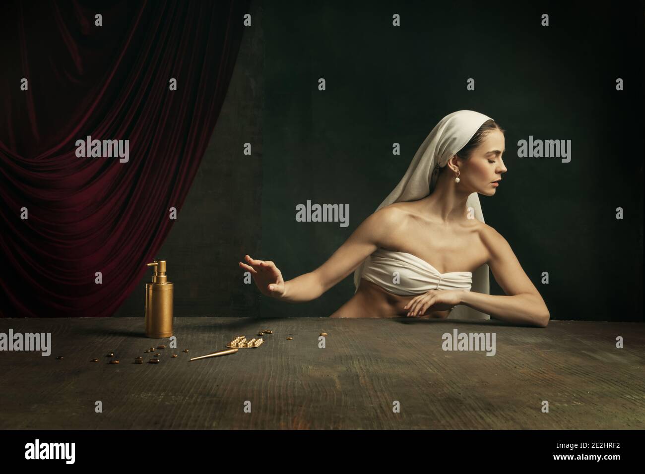 Trattamento. Moderna remake di opere d'arte classica con tema coronavirus - giovane donna medievale su sfondo scuro prendendo pillole di colore dorato. Concetto di coronavirus, pandemia, creatività, arte Foto Stock