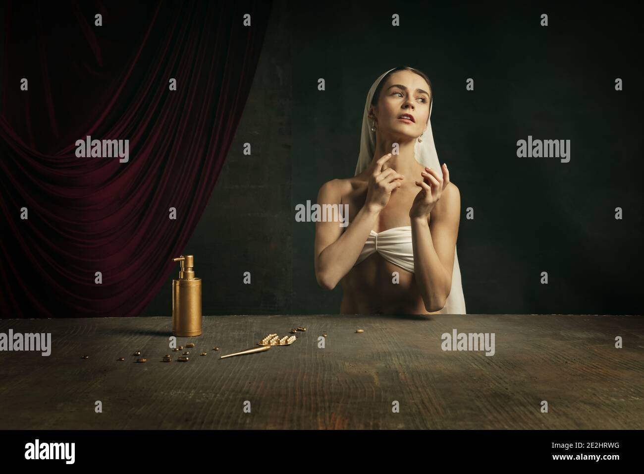 Trattamento. Moderna remake di opere d'arte classica con tema coronavirus - giovane donna medievale su sfondo scuro prendendo pillole di colore dorato. Concetto di coronavirus, pandemia, creatività, arte Foto Stock