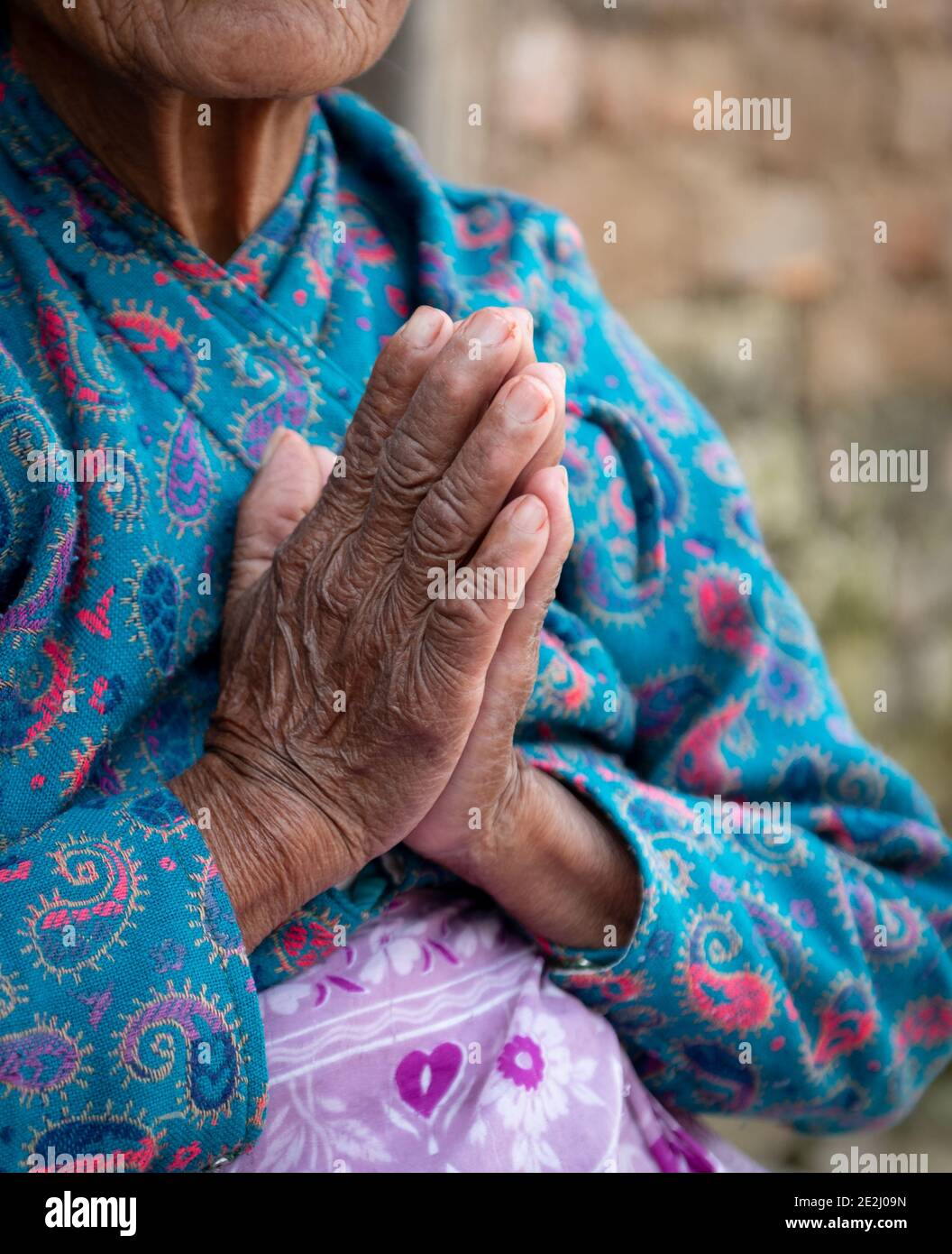 Donna anziana non riconosciuta che indossa panni blu che attraversano le sue mani rughe. Processo di invecchiamento Foto Stock