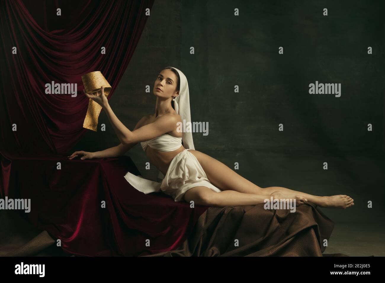 Posa bella. Moderna remake di opere d'arte classiche con tema coronavirus - giovane donna medievale su sfondo scuro con carta igienica dorata. Concetto di coronavirus, pandemia, creatività, arte Foto Stock