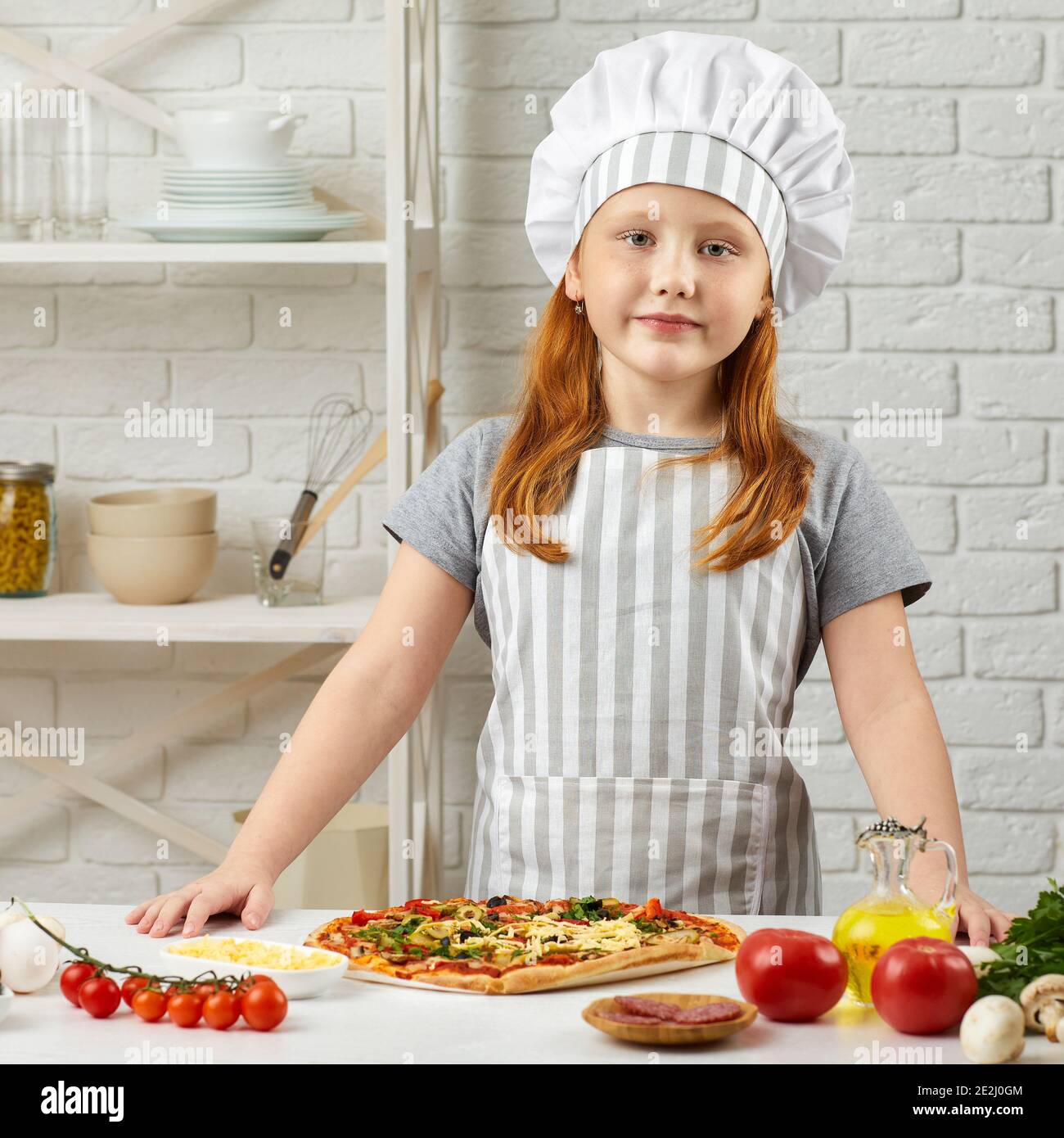 bambina in cappello chef e un grembiule cucina pizza in cucina Foto stock -  Alamy