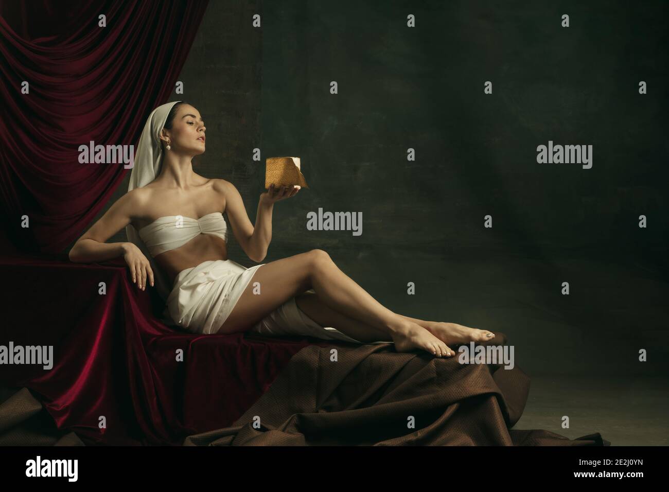 Posa bella. Moderna remake di opere d'arte classiche con tema coronavirus - giovane donna medievale su sfondo scuro con carta igienica dorata. Concetto di coronavirus, pandemia, creatività, arte Foto Stock