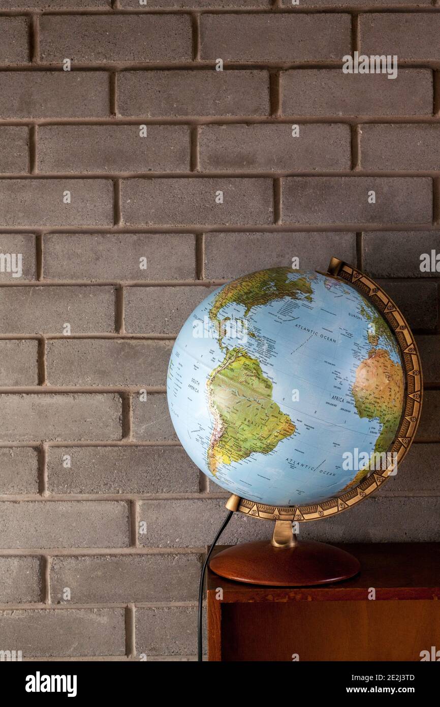 Globo sulla parte superiore della libreria vintage davanti al mattone parete Foto Stock