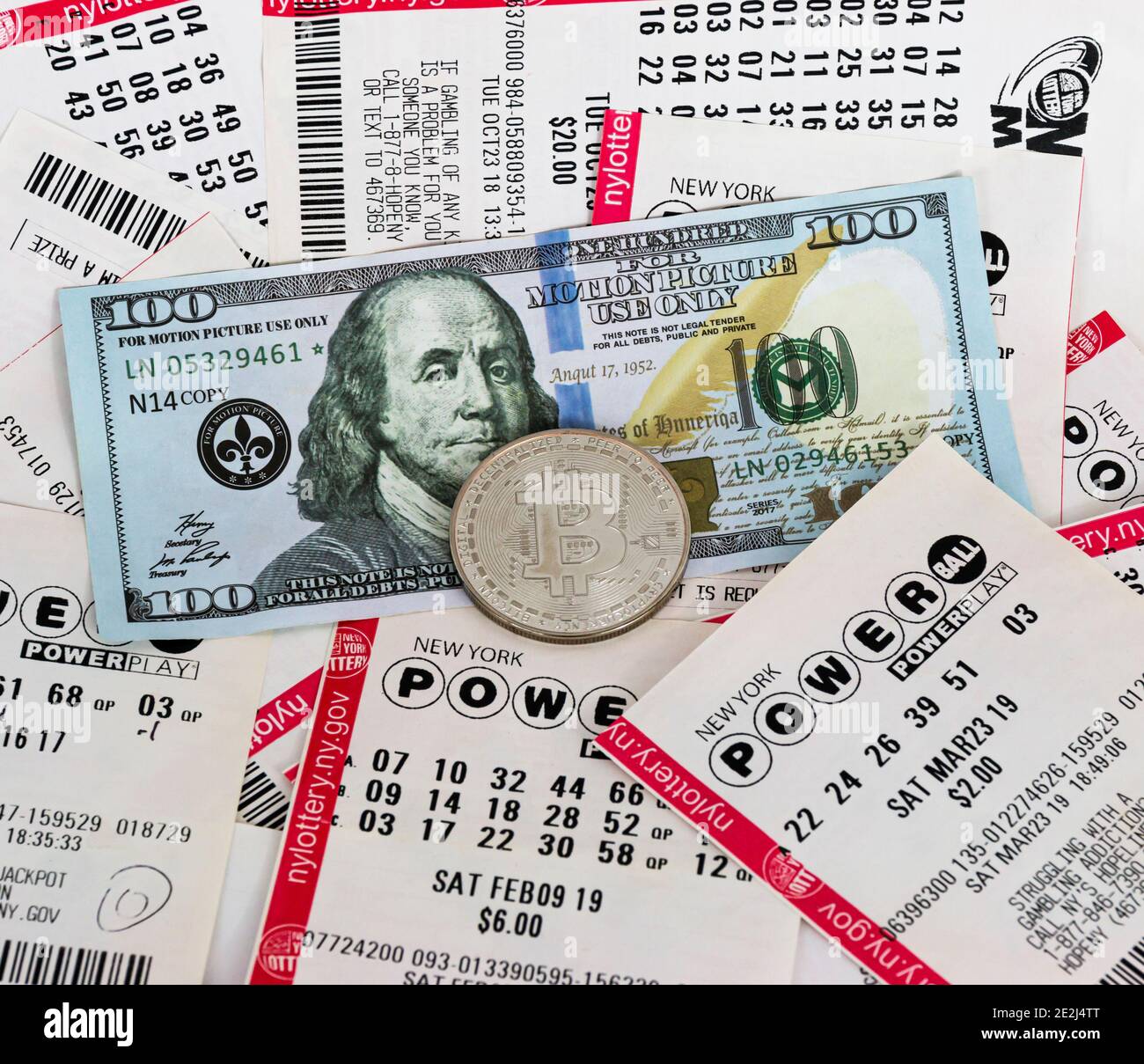 Babylon, New York, USA - 10 Janurary 2021: Una moneta di bitcoin d'argento in cima ai biglietti della lotteria e un conto di cento dollari che dà il concetto di tutto Foto Stock