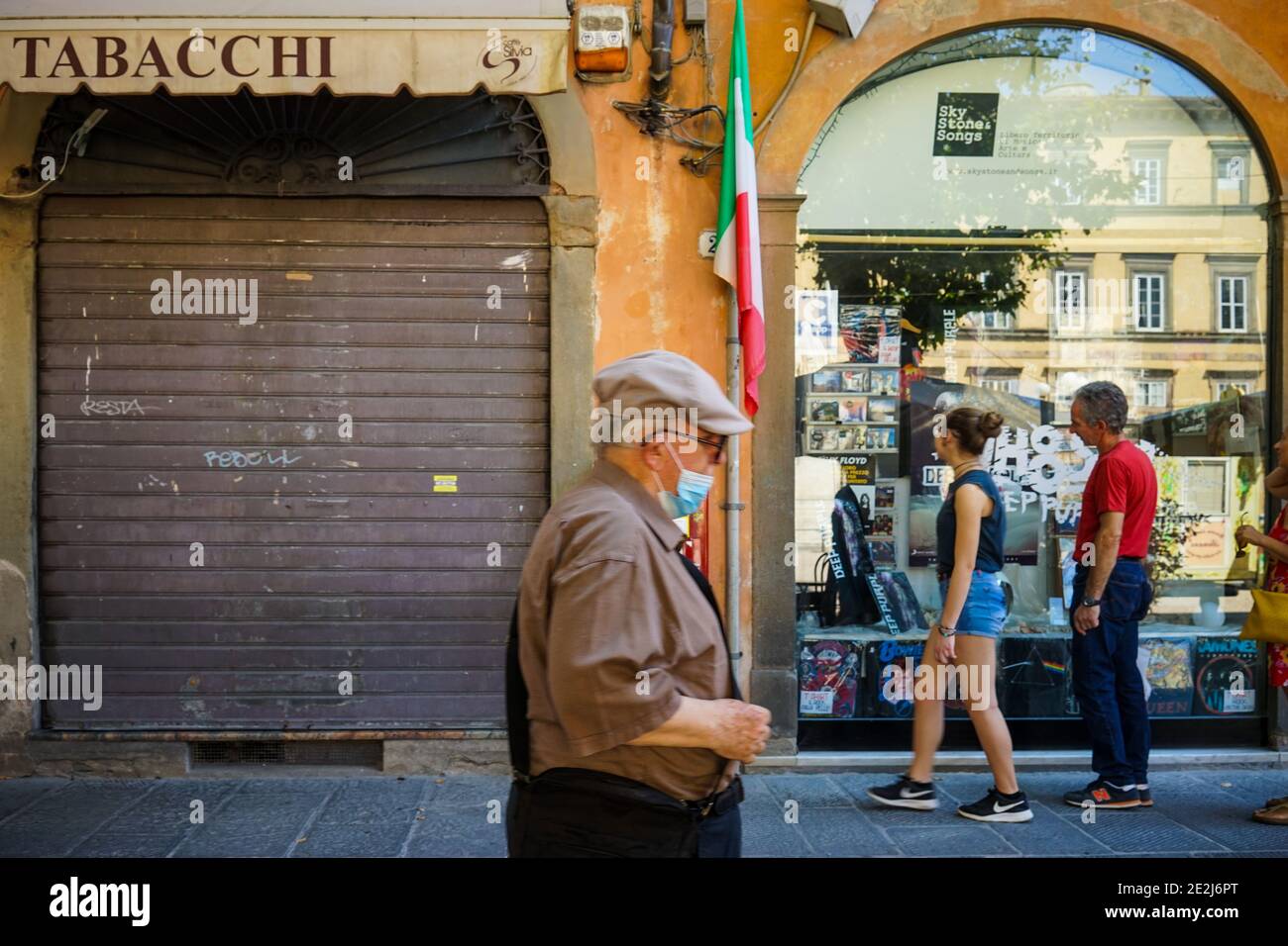 Un anziano con una maschera di protezione cocid19 davanti a. un negozio Foto Stock