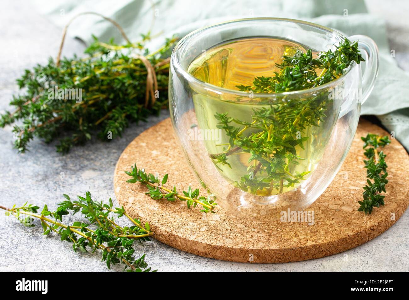 Tisana terapeutica. Tazza calda di tè al timo su un piano di pietra chiaro. Foto Stock