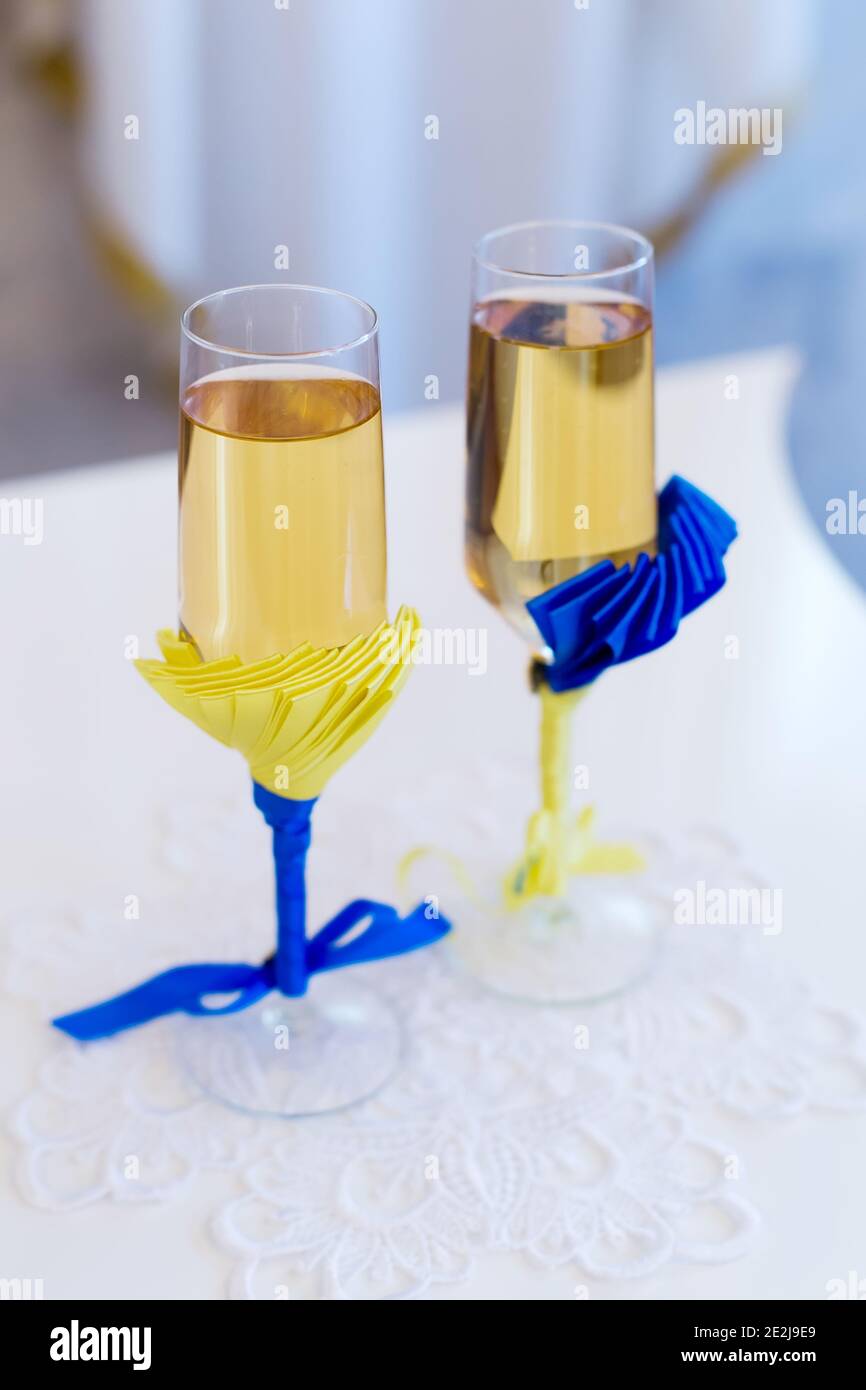 Due bicchieri da sposa con champagne per coppia con blu e. decorazione nastri gialli Foto Stock