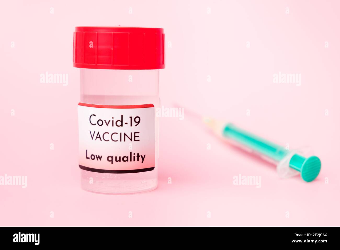 Vaccino Covid-19 di bassa qualità in flacone e siringa monouso per iniezione su fondo rosa. Prevenzione del coronavirus, Sars-Cov-2. Foto Stock
