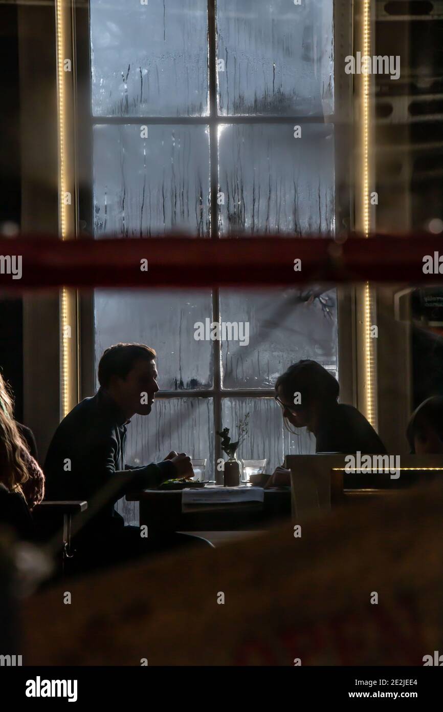 Due persone seduti in una caffetteria in silhouette Foto Stock