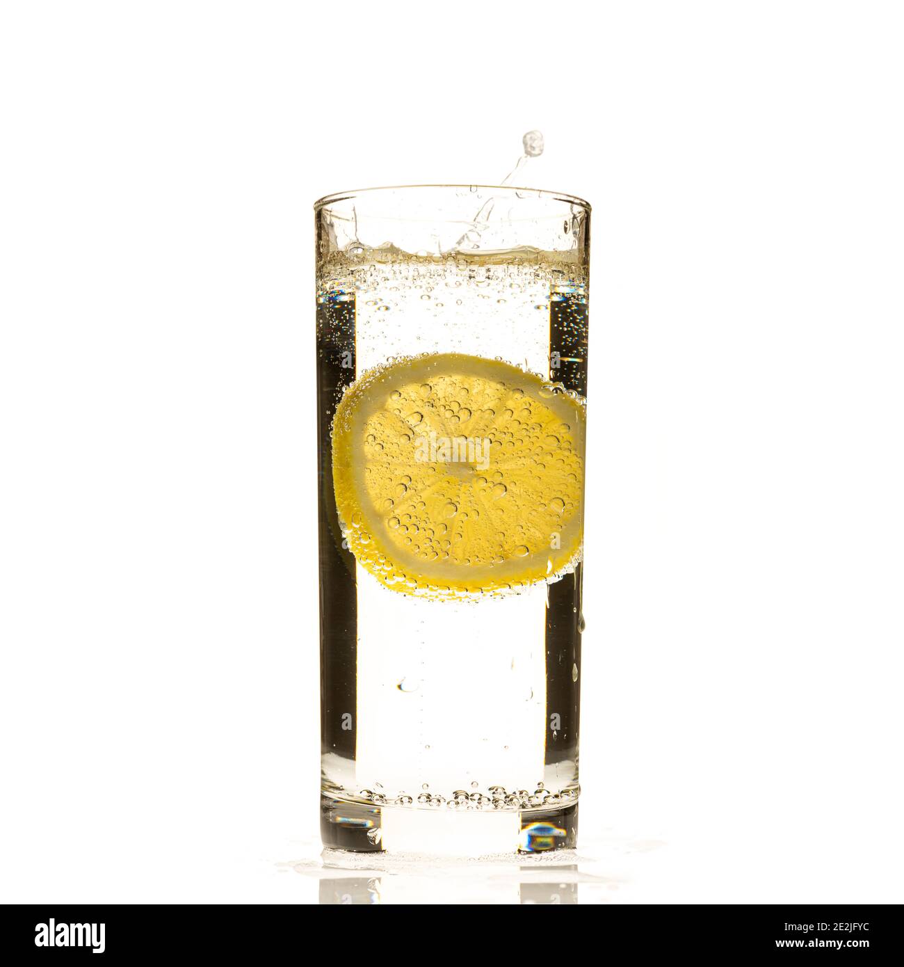 Fetta di limone che si spruzzi in un bicchiere d'acqua Foto Stock