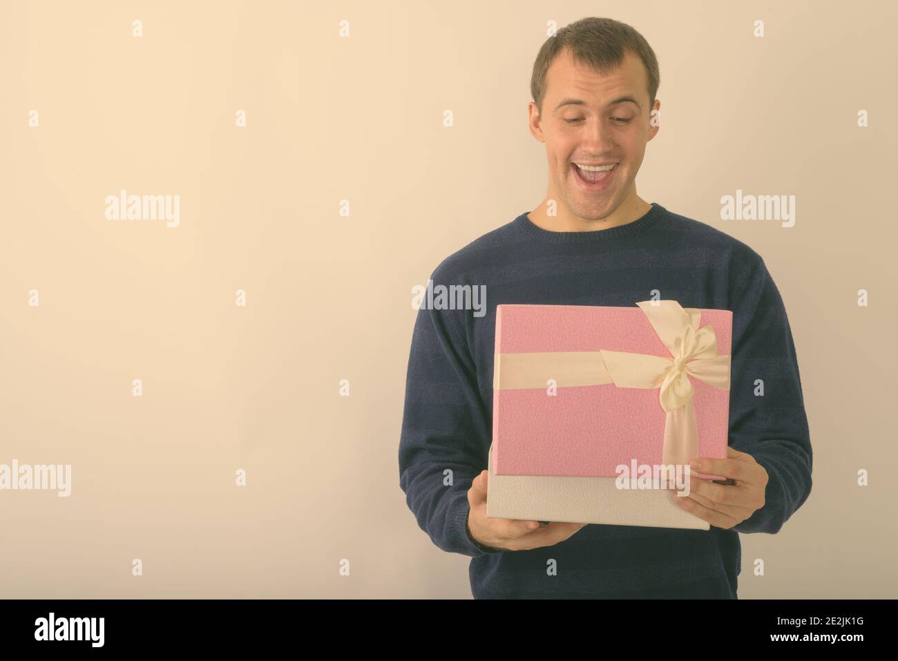 Studio shot di giovani felici muscolare di uomo sorridente durante l'apertura della confezione regalo contro uno sfondo bianco Foto Stock
