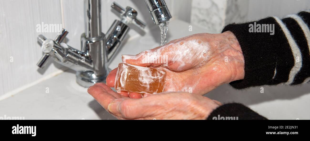 Inghilterra, Regno Unito. 2021. Una donna anziana che si lava le mani prima di fare un test di coronavirus domestico da oggetti sul davanzale. Foto Stock