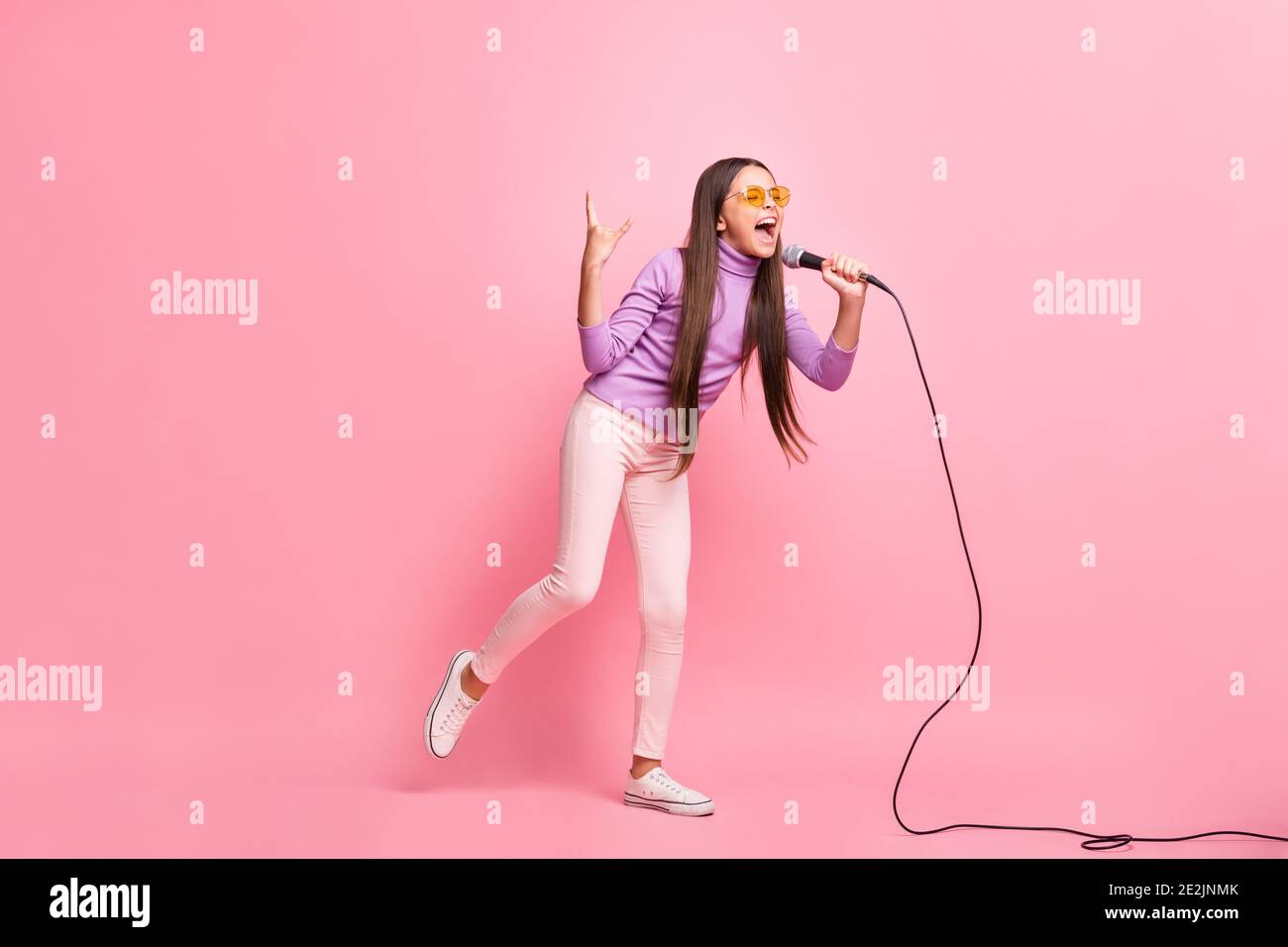 Foto a dimensione intera di cazzo ragazzino canta canzone in mic show il segno cornuto isolato su sfondo di colore pastello Foto Stock