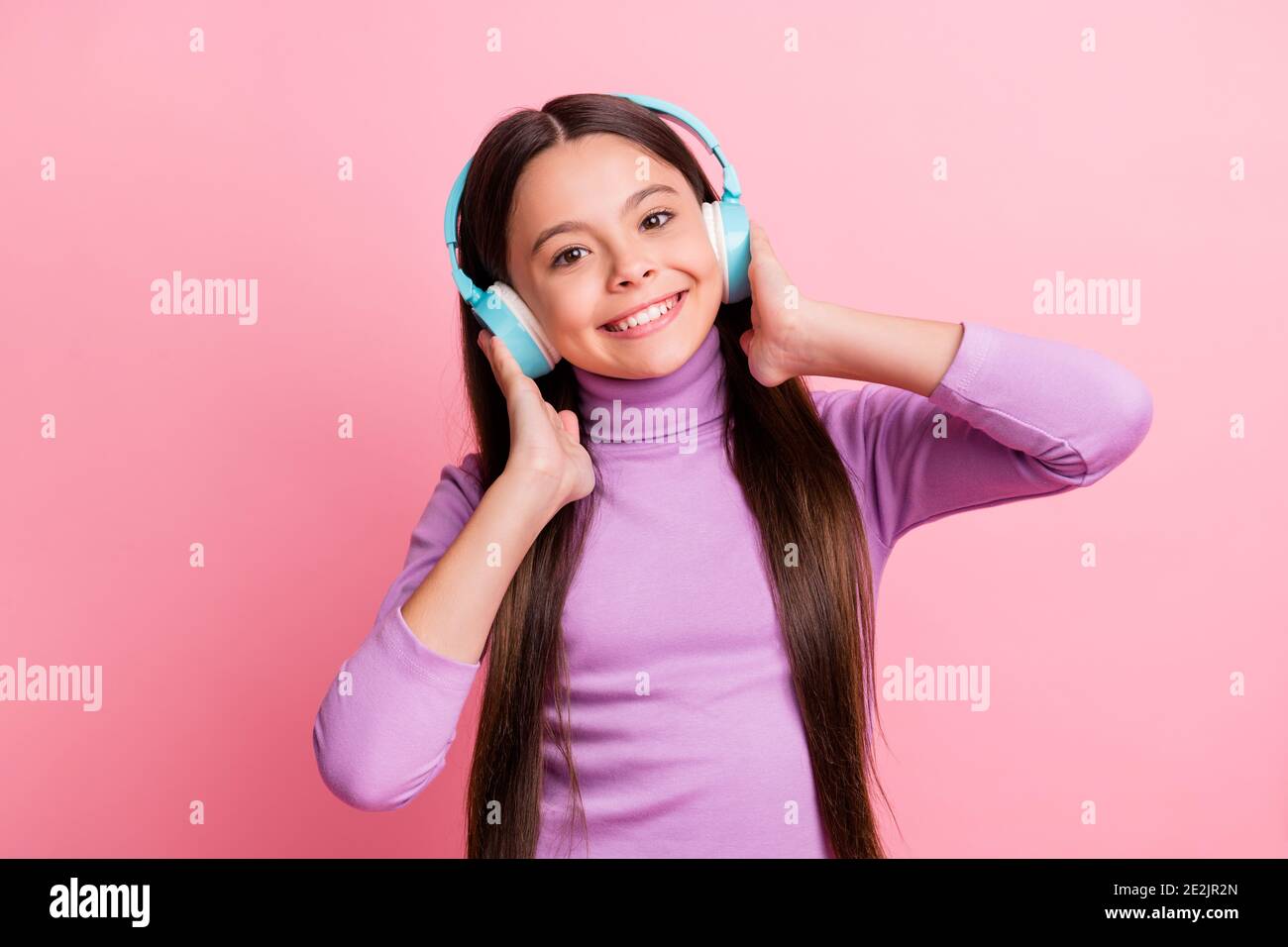 Foto di una bambina positiva ascoltate la canzone in modalità wireless auricolare isolato su sfondo color pastello Foto Stock
