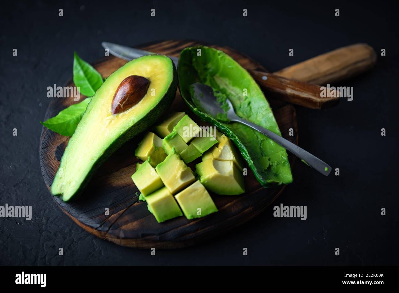 Frutta fresca all'avocado su tavola di legno con cucchiaio e coltello. Il concetto di alimentazione sana. Fotografia alimentare Foto Stock
