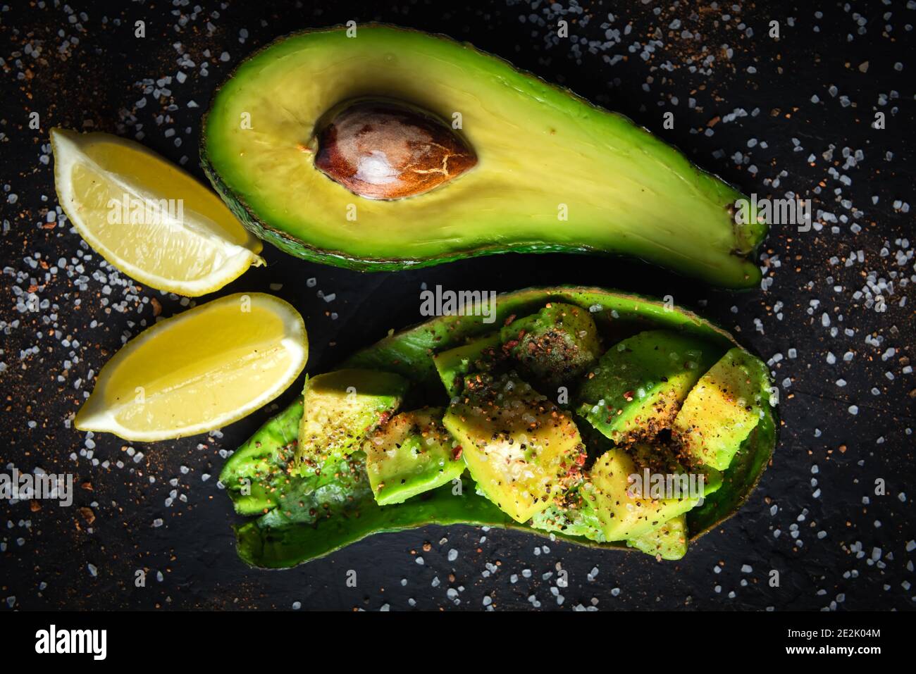 Fresco frutto di avocado su un nero scheda rustico. Il concetto di mangiare sano. Fotografia di cibo Foto Stock