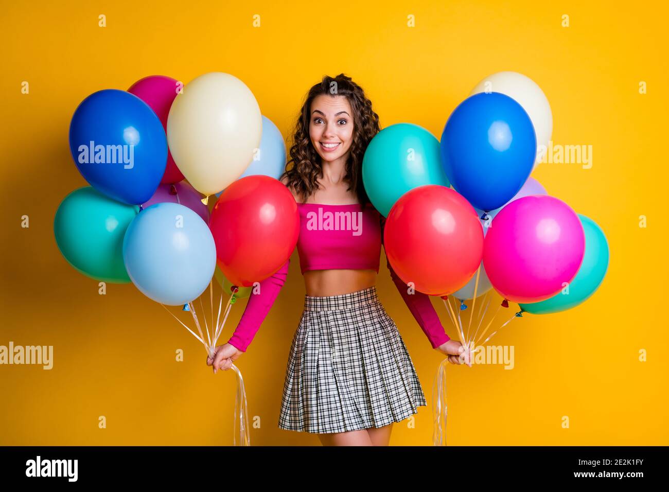 Ritratto foto di funky positivo ragazza che indossa casual Outlook con gonna  a scacchi che tiene i palloncini d'aria in entrambe le mani isolate colore  giallo brillante Foto stock - Alamy