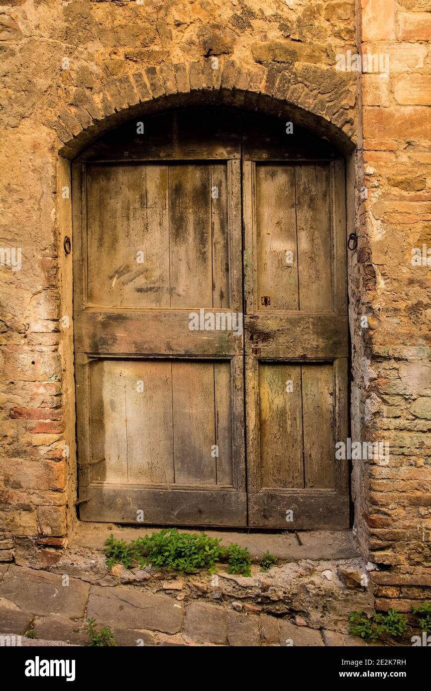 Una vecchia porta in legno in un palazzo residenziale in disuso nel villaggio di Montalcino in provincia di Siena, Toscana, Italia Foto Stock