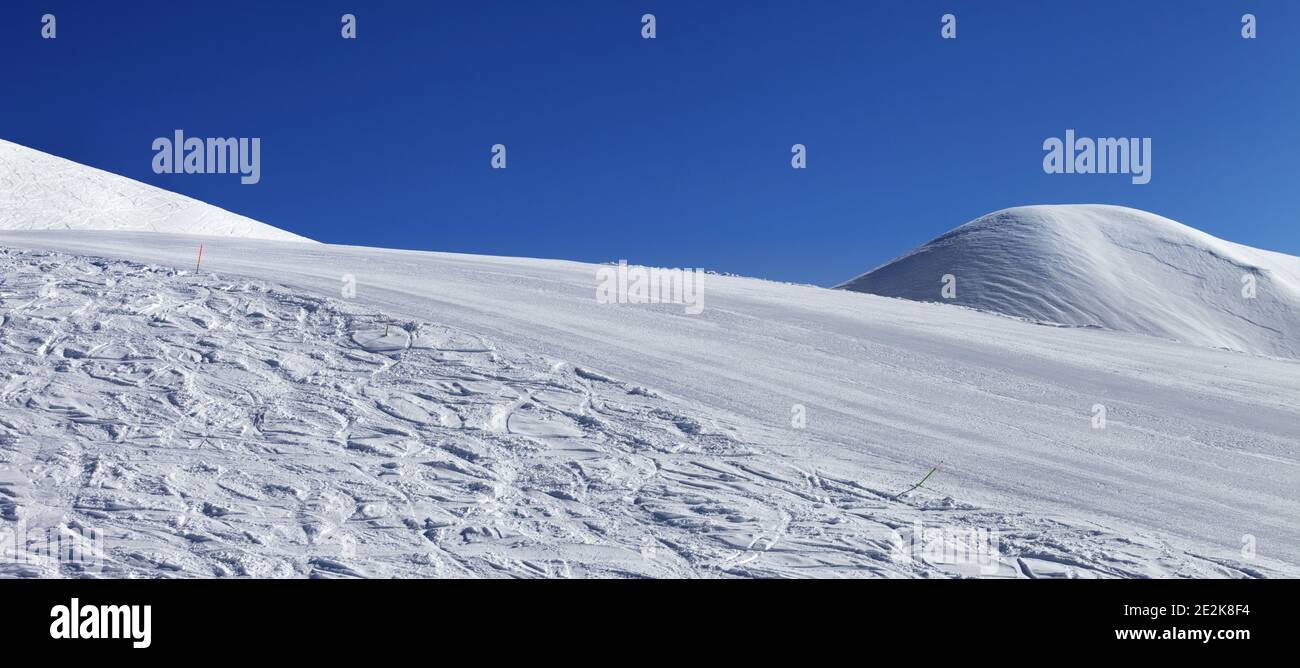 Vista panoramica sulle piste da sci innevate con tracce da sci e snowboard e cielo blu chiaro in bella giornata invernale. Georgia, regione Gudauri. Caucaso Mountai Foto Stock