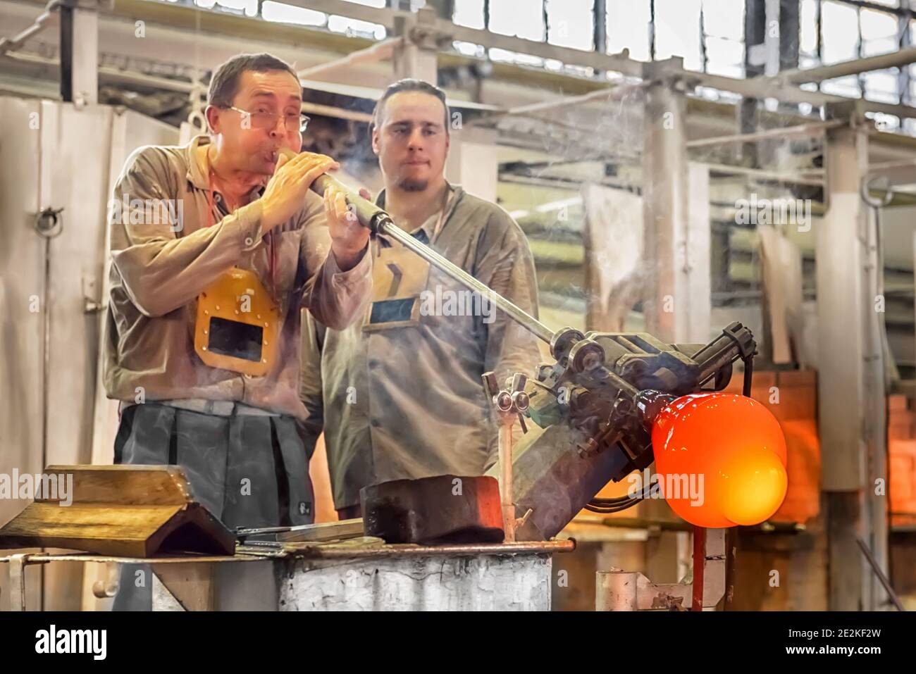 Trasformare una massa calda di vetro prelevata da un forno caldo in un'opera d'arte. Maestro di vetro che soffia un vaso in Moser Gla Foto Stock