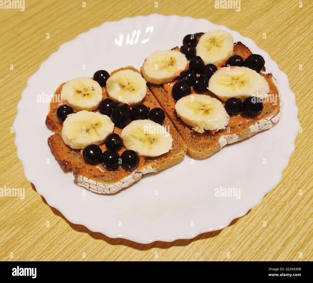 Un dessert sano per colazione, pranzo o cena pane scuro con burro di arachidi, ribes nero e fette di banana Foto Stock