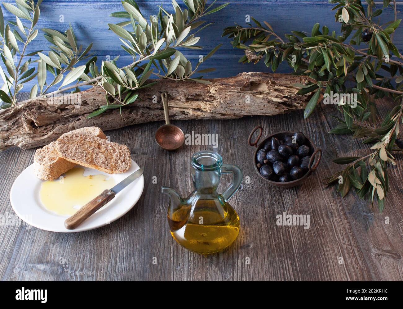 Ancora vita con un vaso di olio, rami di olive, olive e pane con olio. Foto Stock