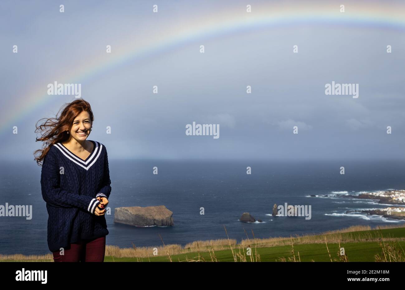 Giovane donna sorridente sotto arcobaleno, villaggio di Mosteiros, isole Azzorre. Foto Stock