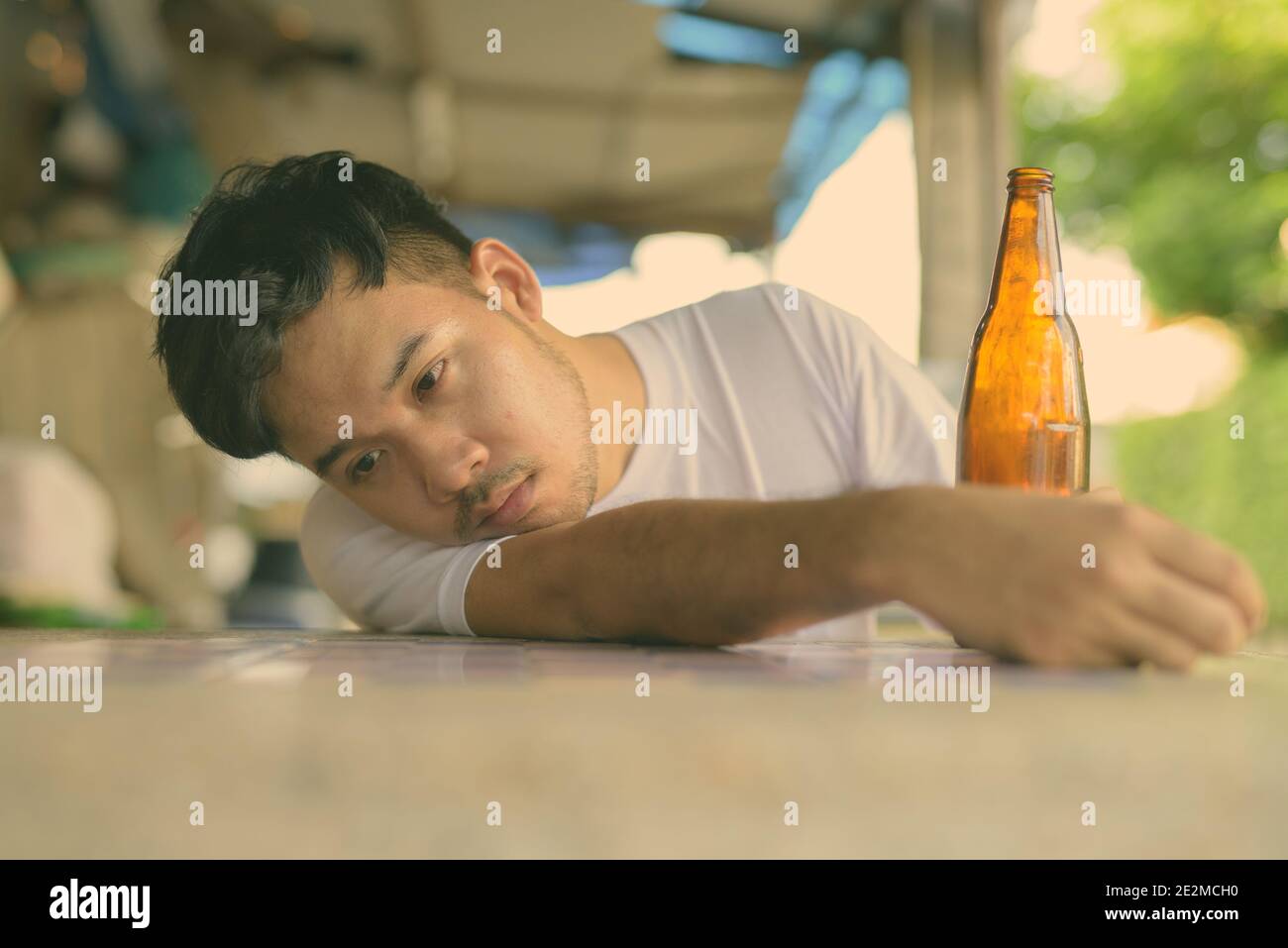 Giovane uomo asiatico ubriacarsi nelle strade all'aperto Foto Stock