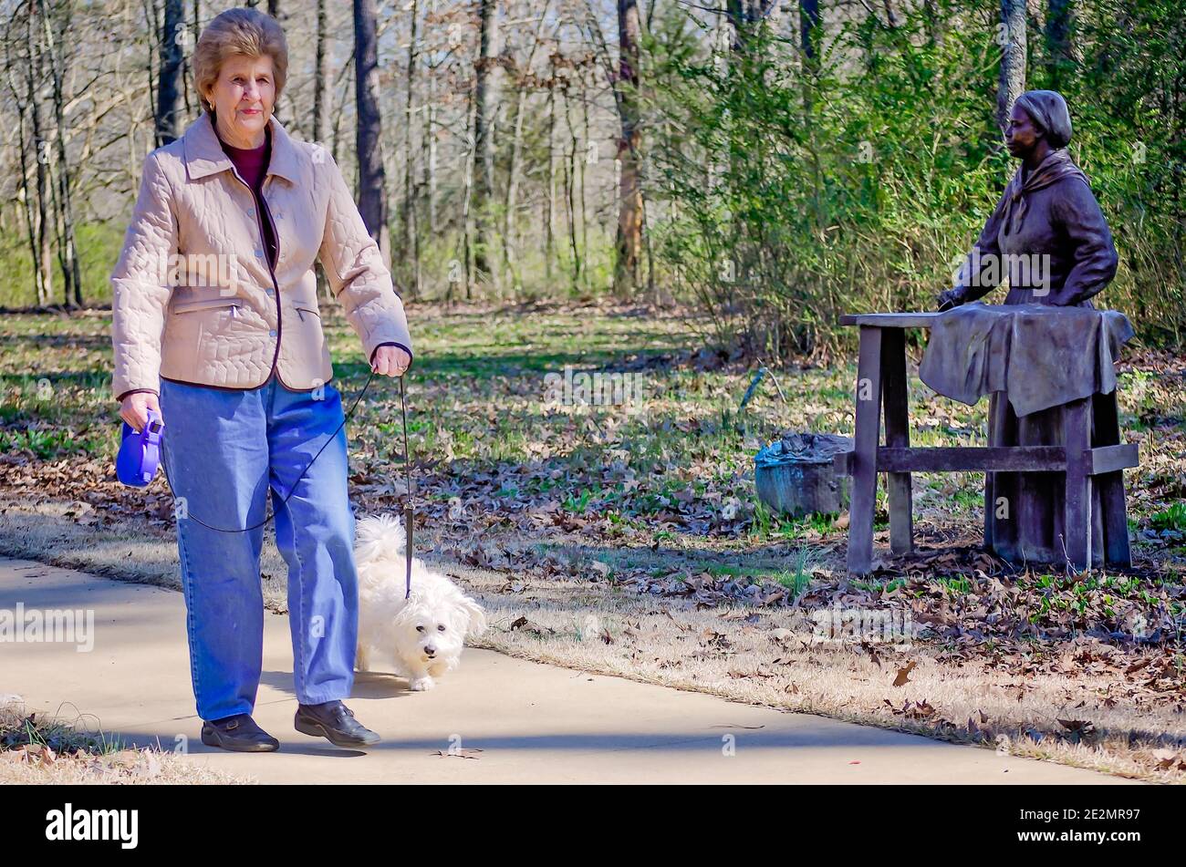 Una donna cammina il suo cane davanti a una statua di bronzo di una donna che stira al campo di Corinth Contraband a Corinth, Mississippi 5 marzo 2012. Foto Stock