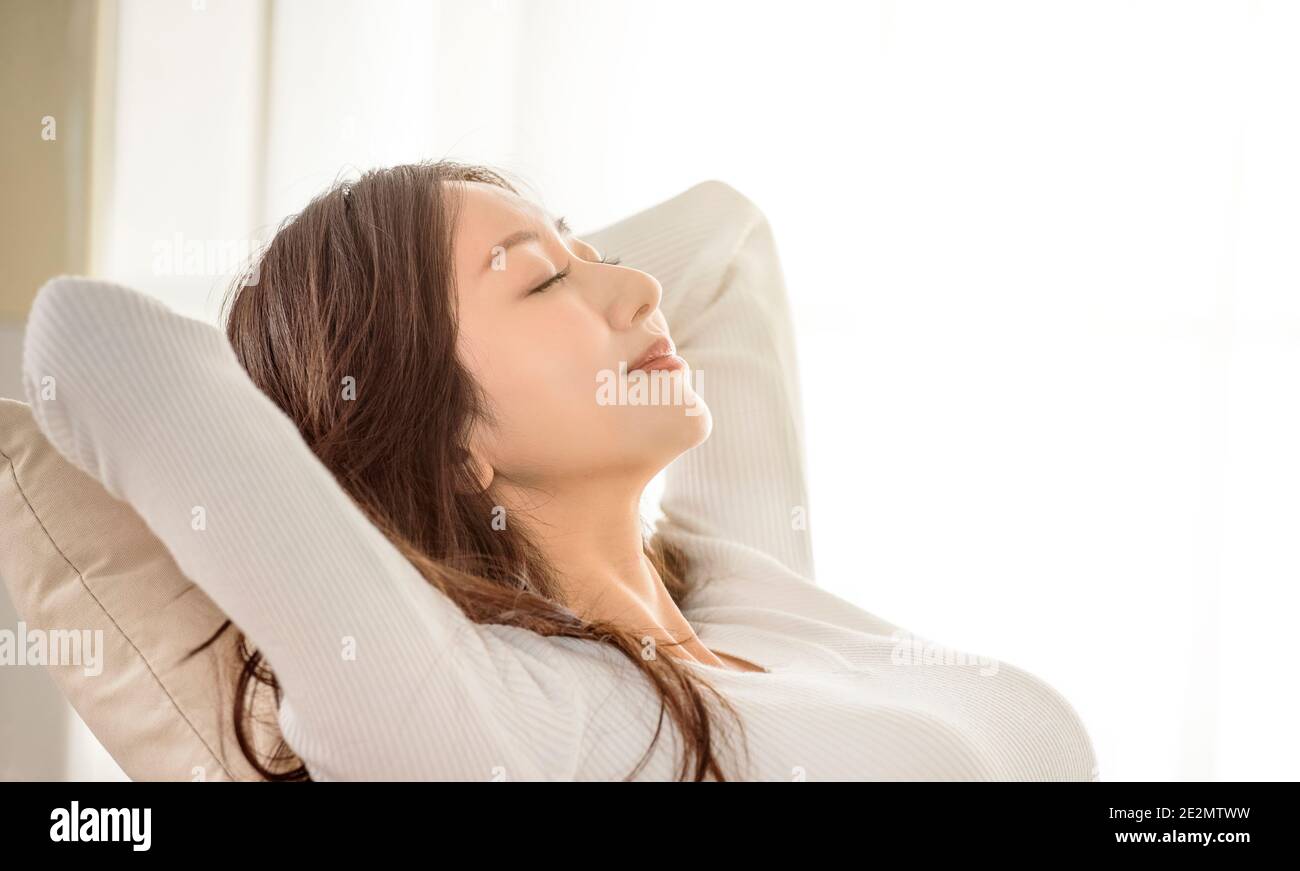 Giovane donna rilassata appoggiata sul divano e gli occhi chiusi Foto Stock