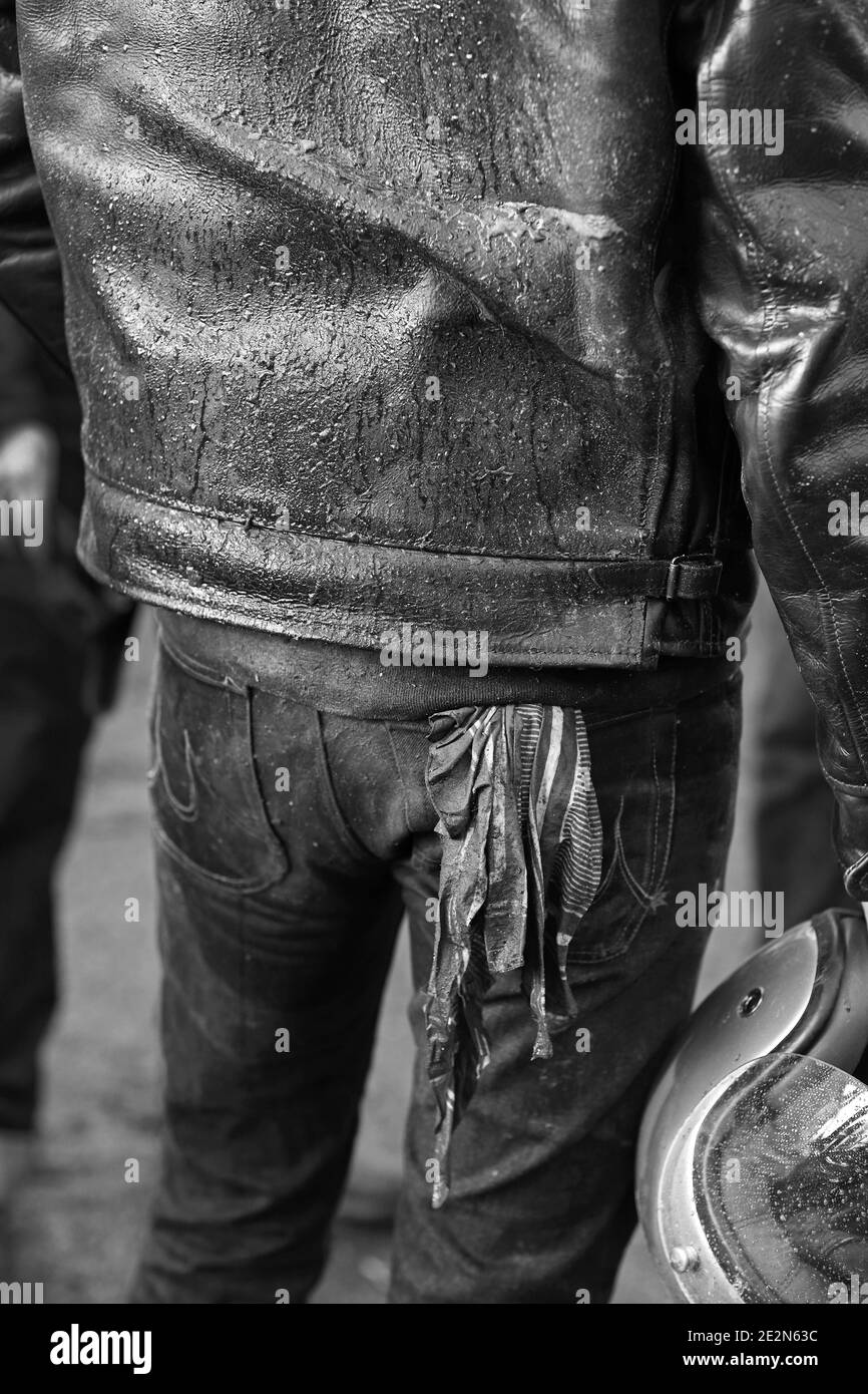 Vista posteriore dell'uomo che indossa una giacca in similpelle, jeans con tasca posteriore quadrata e casco per moto da trasporto. Foto Stock