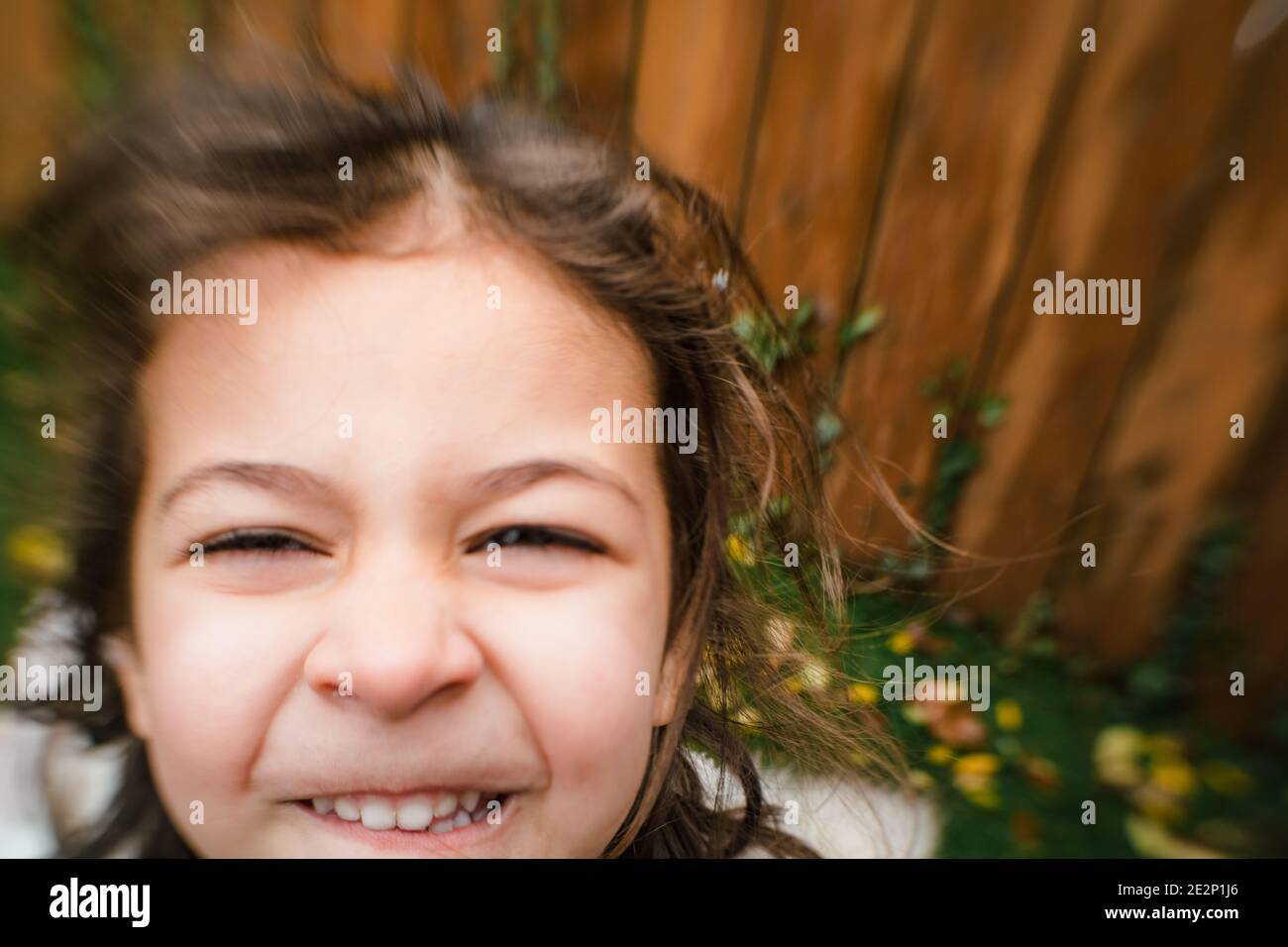 primo piano della bambina che sorride all'esterno con la sfocatura dell'obiettivo effetto Foto Stock