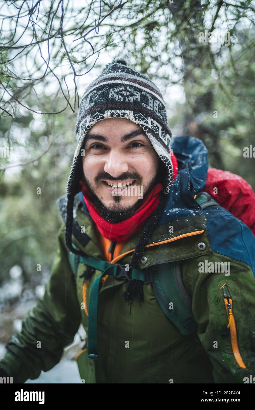 Uomo sorridente a macchina fotografica con protezione fredda in una neve foresta Foto Stock