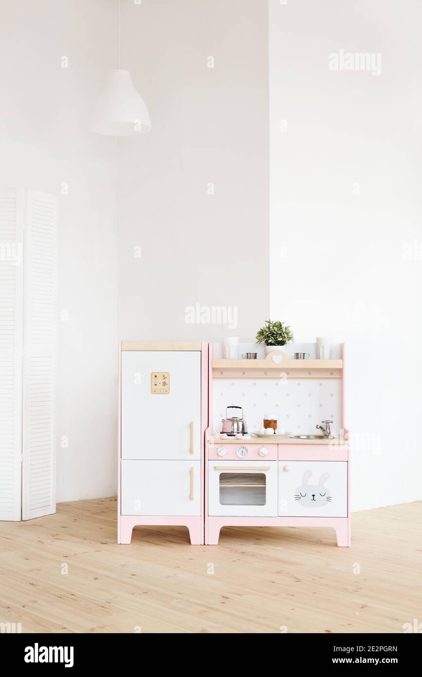 Mobili da gioco per bambini. Cucina in legno rosa e bianco con frigorifero,  piano cottura, forno e lavandino in grande spazio copia della stanza  luminosa Foto stock - Alamy