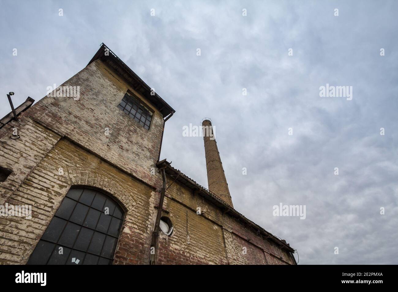 Abbandonata fabbrica e magazzino con il suo caratteristico camino in mattoni nell'Europa orientale, a Belgrado, Serbia, ex Jugoslavia, durante un pomeriggio nuvoloso Foto Stock