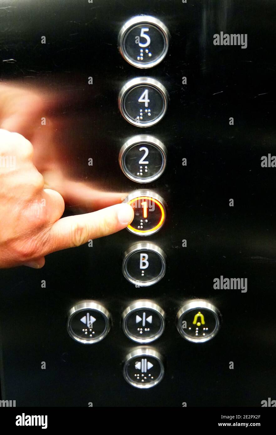 Reykjavik, Islanda - 21 giugno 2019 - una mano che tocca i pulsanti dell'ascensore con alfabeto romano e lettere Braille Foto Stock