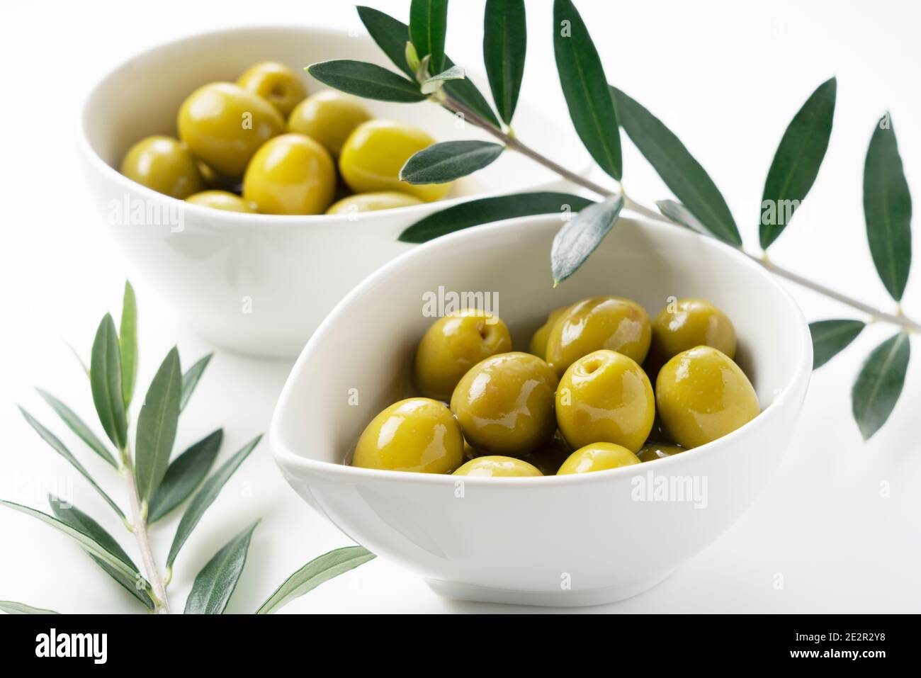 Olive salate e rami d'oliva posti su sfondo bianco Foto Stock