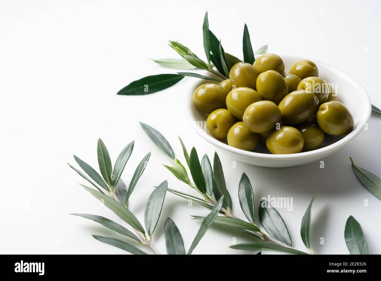 Olive salate e rami d'oliva posti su sfondo bianco con spazio per la copia Foto Stock